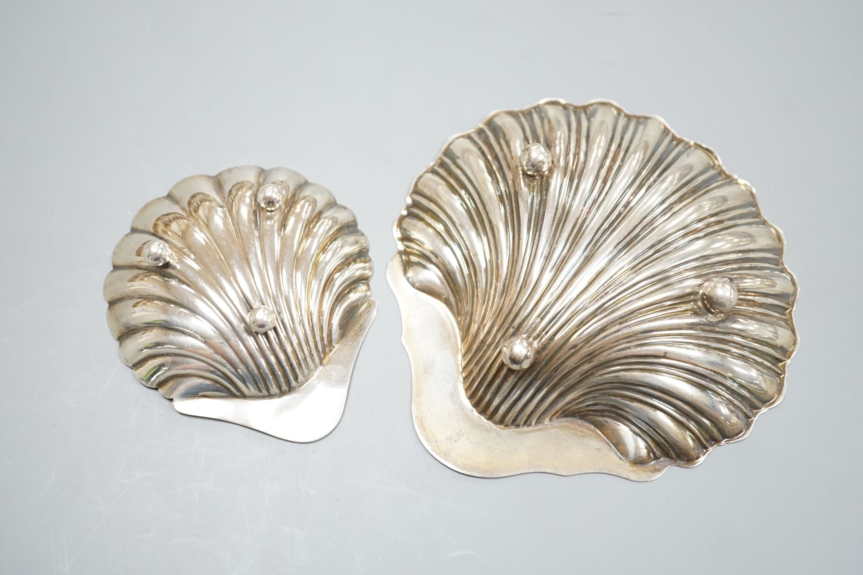 A scallop shell butter dish on three ball feet, Sheffield 1926, 94mm and an earlier larger silver butter shell, London, 1905, 112 grams.